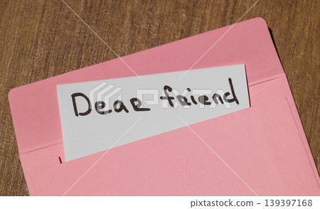 Handwritten note saying Dear friend peeking out of a pink envelope Handwritten note saying Dear friend peeking out of a pink envelope 139397168