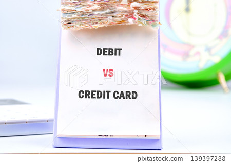A white flip chart stands on a light-colored desk, prominently featuring the text Debit vs Credit Card for financial education 139397288