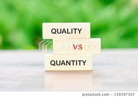 Stacked wooden blocks display the words QUALITY VS QUANTITY, representing a fundamental business or personal decision on a light gray table with a soft green backdrop Stacked wooden blocks display the words QUALITY VS QUANTITY, representing a fundamental business or personal decision on a light gray table with a soft green backdrop 139397307