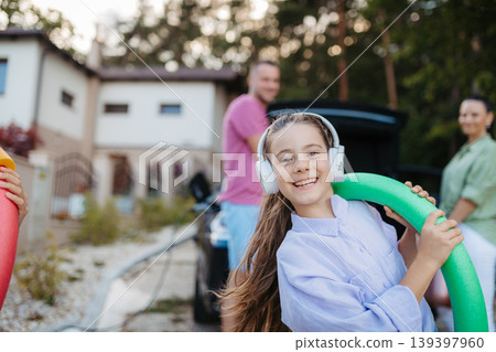 Happy family preparing for holiday, putting suitcases in car trunk, while their electric car charging. Happy family preparing for holiday, putting suitcases in car trunk, while their electric car charging. 139397960