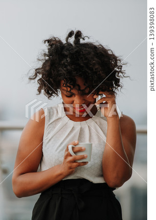 A businesswoman standing on terrace in modern office, making phone call. A businesswoman standing on terrace in modern office, making phone call. 139398083
