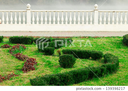Manicured garden with ornate balustrade overlooking misty water 139398217