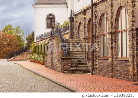 Stone staircase leading up to a historic building with arched windows and autumn trees Stone staircase leading up to a historic building with arched windows and autumn trees 139398233