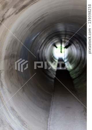 Light and shadow in a concrete pipe tunnel in a park_vertical 139398258