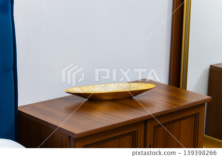 Elegant golden decorative bowl on a wooden nightstand with a mirror reflection Elegant golden decorative bowl on a wooden nightstand with a mirror reflection 139398266