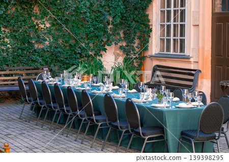Elegant outdoor dining table set for a formal event in a vintage courtyard setting Elegant outdoor dining table set for a formal event in a vintage courtyard setting 139398295