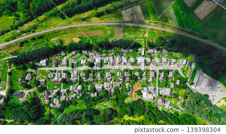 Aerial view of a rural village with houses, fields, and a railway line curving through the landscape Aerial view of a rural village with houses, fields, and a railway line curving through the landscape 139398304