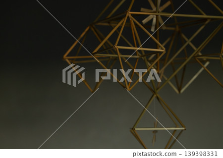 Geometric straw ornament hanging indoors with soft focus and warm lighting dusk interior abstraction Geometric straw ornament hanging indoors with soft focus and warm lighting dusk interior abstraction 139398331