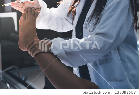 Doctor examining and supporting injured ankle of female patient in hospital room, providing medical assistance and treatment for sprain or fracture Doctor examining and supporting injured ankle of female patient in hospital room, providing medical assistance and treatment for sprain or fracture 139398598