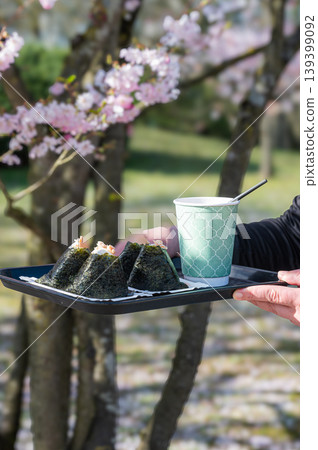Street food moment. Casual park setting showcasing Japanese snack with cherry blossoms Street food moment. Casual park setting showcasing Japanese snack with cherry blossoms 139399092