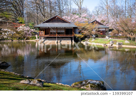 Timeless traditional teahouse reflected in serene pond within peaceful garden setting Timeless traditional teahouse reflected in serene pond within peaceful garden setting 139399107