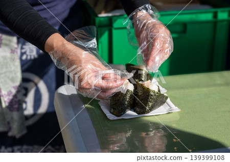 Vendor molds rice. Casual market scene where vendor expertly shapes onigiri for customers Vendor molds rice. Casual market scene where vendor expertly shapes onigiri for customers 139399108