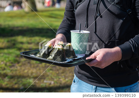 Casual street food presentation detailed. Vendor offers rice balls in natural setting Casual street food presentation detailed. Vendor offers rice balls in natural setting 139399110