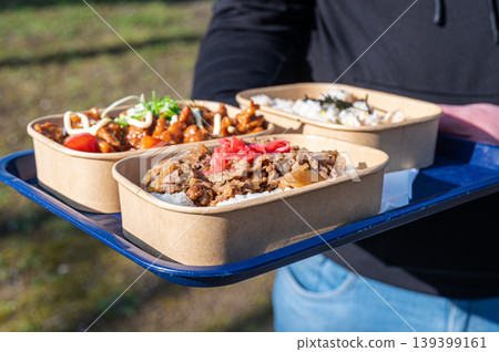 Friends sharing homemade lunch outdoors. Group enjoying sunny day with delicious bento in park Friends sharing homemade lunch outdoors. Group enjoying sunny day with delicious bento in park 139399161