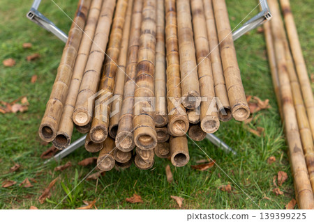 Natural bamboo poles stacked on grass for garden building projects 139399225