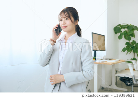 A young businesswoman talking on her smartphone; an office worker answering the phone in the office. 139399621