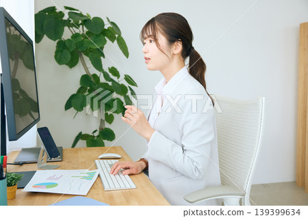 A young businesswoman working on a computer at her desk / an office worker working in an office A young businesswoman working on a computer at her desk / an office worker working in an office 139399634