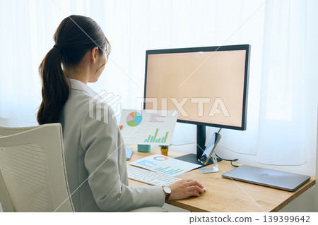 A young businesswoman working on a computer at her desk / an office worker working in an office A young businesswoman working on a computer at her desk / an office worker working in an office 139399642