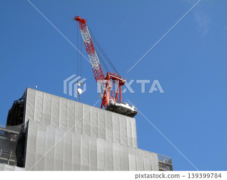 A tower crane at a building construction site against a blue sky. 139399784