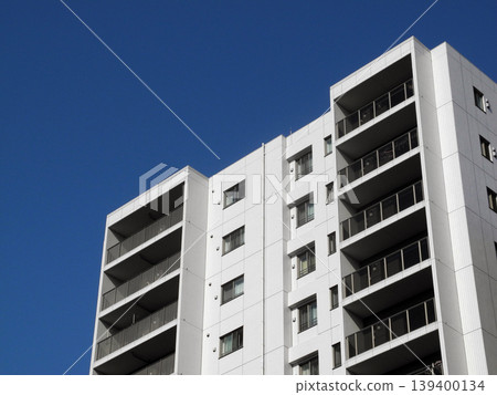 A white apartment building against a blue sky. A white apartment building against a blue sky. 139400134