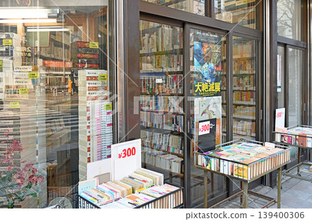神保町的一家二手書店,一輛裝滿色彩鮮豔的平裝書的手推車,每本售價 300 日元,以及街角。 神保町的一家二手書店,一輛裝滿色彩鮮豔的平裝書的手推車,每本售價 300 日元,以及街角。 139400306