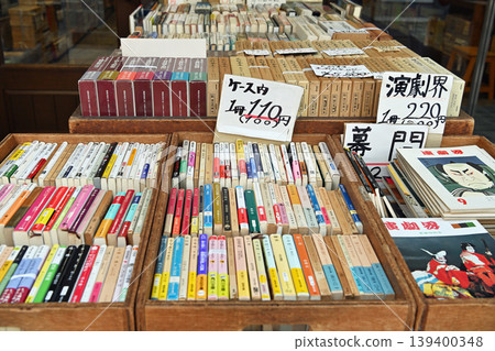 A used bookstore in Jinbocho: Wooden fixtures displaying theater magazines and specialized books, along with warm, handwritten signs. 139400348