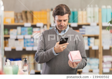 Man in pharmacy scans QR code on emollient cream product 139400502
