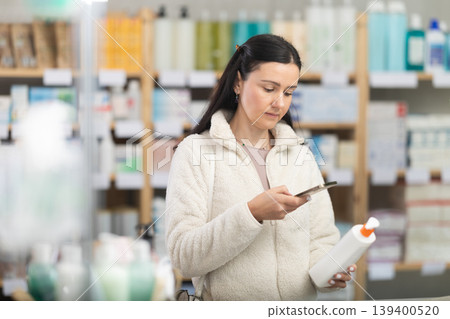 Woman in pharmacy scans QR code on emollient cream product 139400520