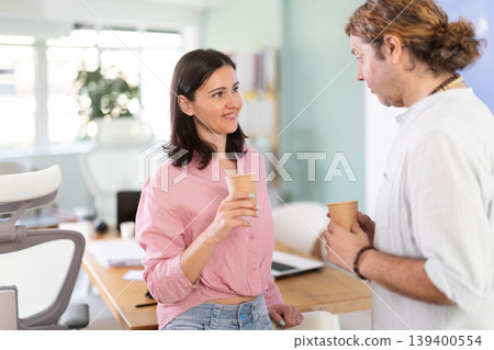 Adult man and woman drinking coffee in office Adult man and woman drinking coffee in office 139400554
