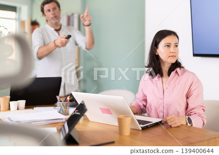 Middle-aged male and female colleagues watching project presentation in office Middle-aged male and female colleagues watching project presentation in office 139400644