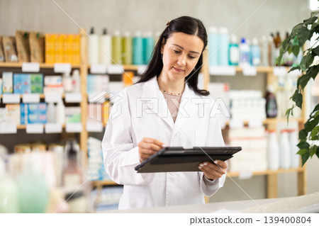 Woman pharmacist makes restock, uses electronic carrier tablet of information Woman pharmacist makes restock, uses electronic carrier tablet of information 139400804