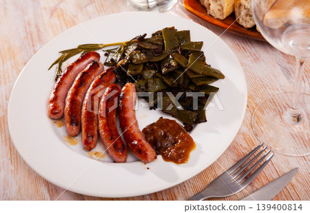 Fried sausages served with green beans at plate 139400814