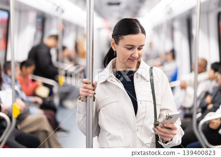Woman using smartphone while traveling in subway car Woman using smartphone while traveling in subway car 139400823
