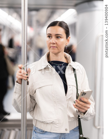 Woman using smartphone while traveling in subway car Woman using smartphone while traveling in subway car 139400984