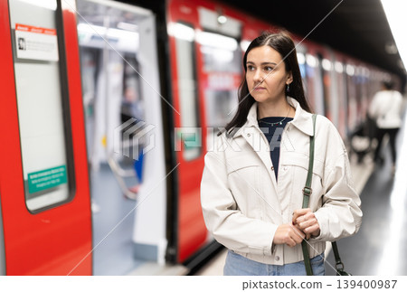 Girl is standing on metro platform station, waiting for transport to arrive Girl is standing on metro platform station, waiting for transport to arrive 139400987