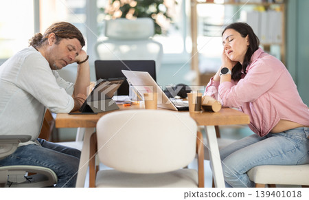 Middle-aged man and woman sleeping at workplace after stressful workday Middle-aged man and woman sleeping at workplace after stressful workday 139401018