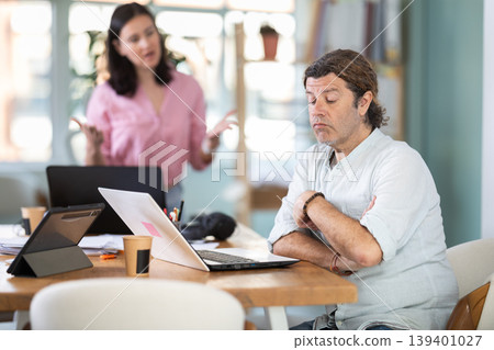 Woman scolding sad colleague sitting at laptop in office 139401027