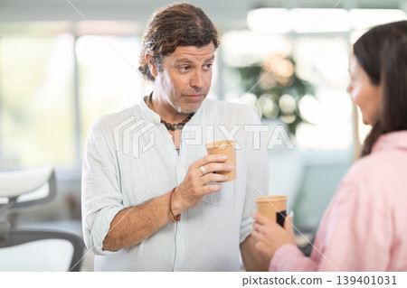 Two office workers drink coffee and chat during work break Two office workers drink coffee and chat during work break 139401031