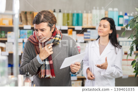 Man with sore throat and cough choosing pills with help from pharmacist 139401035