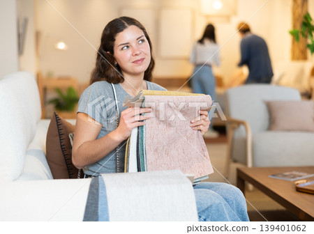 Portrait of woman choosing upholstery fabric in furniture salon Portrait of woman choosing upholstery fabric in furniture salon 139401062