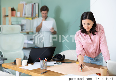 Two architects discuss a building plan in company office 139401071