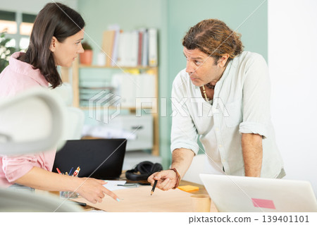 Two architects discuss a building plan in company office 139401101