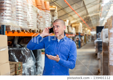 Fulfillment center worker talking on phone in warehouse 139401112