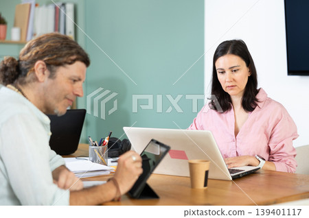 Male and female colleagues working with laptops and tablets 139401117