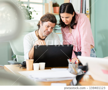 Sad man and woman facing problems while working on laptop in office Sad man and woman facing problems while working on laptop in office 139401123