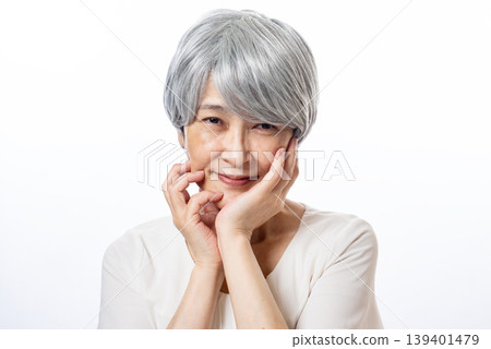 A senior woman with white hair smiles happily, saying that her skin has been looking good lately. A senior woman with white hair smiles happily, saying that her skin has been looking good lately. 139401479