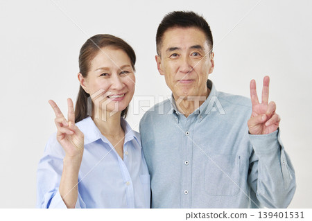 一對面帶微笑的老年夫婦比出和平手勢 139401531