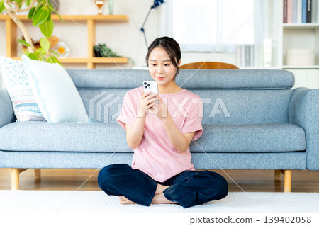在房間裡操作智慧型手機的年輕女子 139402058