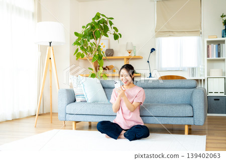 A young woman operating a smartphone in a room A young woman operating a smartphone in a room 139402063