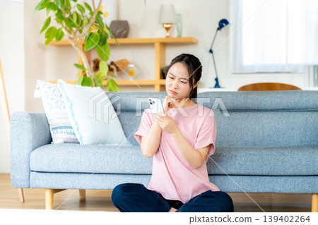 在房間裡操作智慧型手機的年輕女子 在房間裡操作智慧型手機的年輕女子 139402264